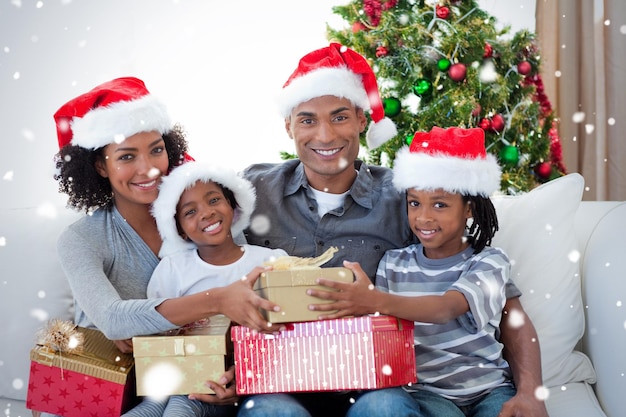 smiling family sharing christmas presents against snow falling