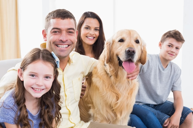 Smiling family sitting with Golden Retriever on sofa