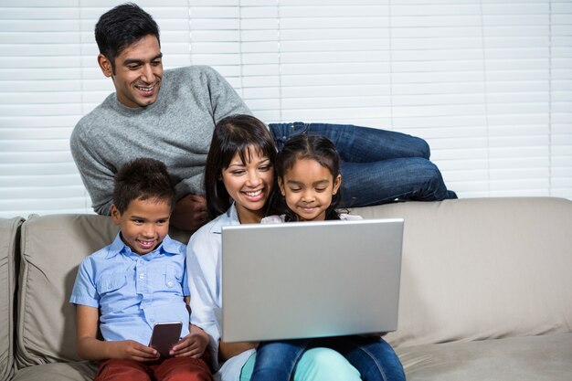 smiling family using laptop on the sofa