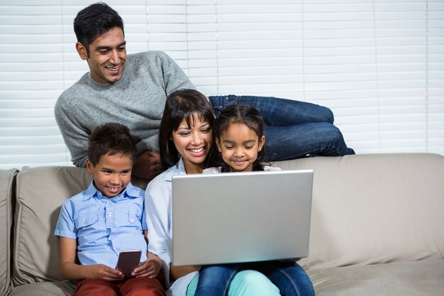 Smiling family using laptop on the sofa