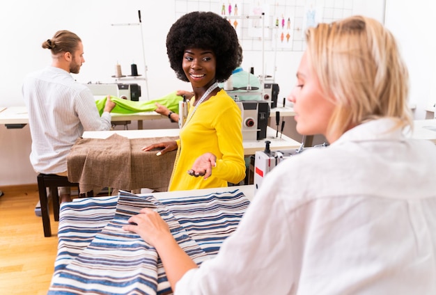 Photo smiling fashion designer talking with colleague at studio