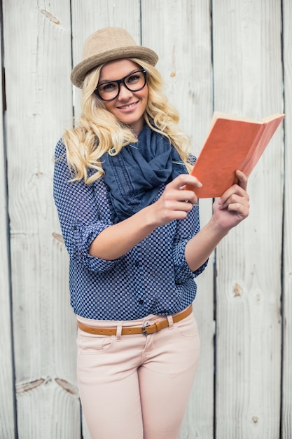 Smiling fashionable blonde holding book outdoors