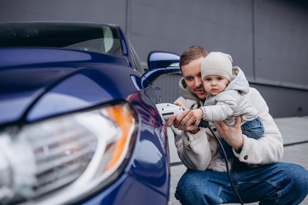 Smiling father and daughter charging electric car at home