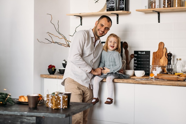 Smiling father and daughter in kitchen at home. 