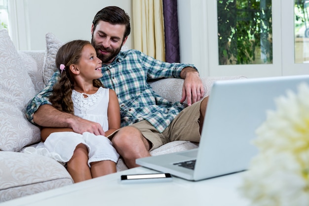 Smiling father and daughter on sofa