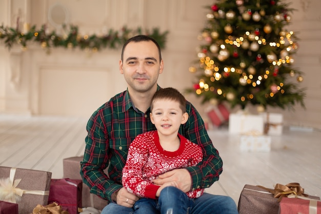 Smiling father hug his sonnear Christmas tree