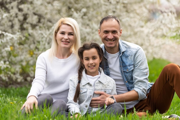 웃는 아버지, 어머니, 딸. Sun Shines on Idyllic Happy Family는 뒷마당에서 즐거운 시간을 보냅니다.