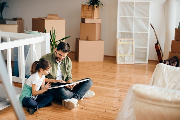 Smiling father reading book to his daughter at their new apartment