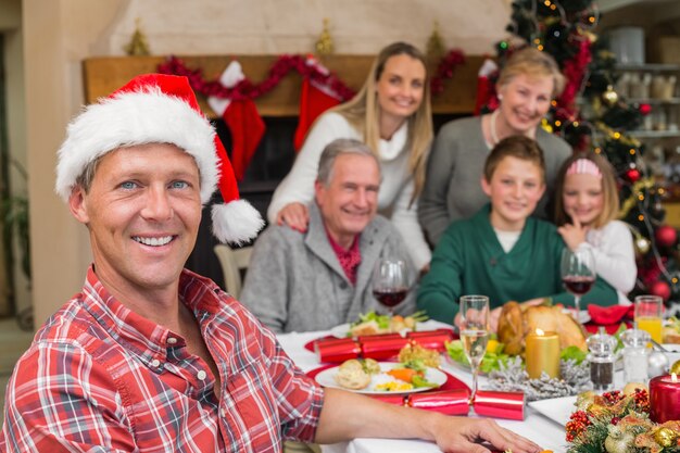 Smiling father in santa hat posing in front of his family