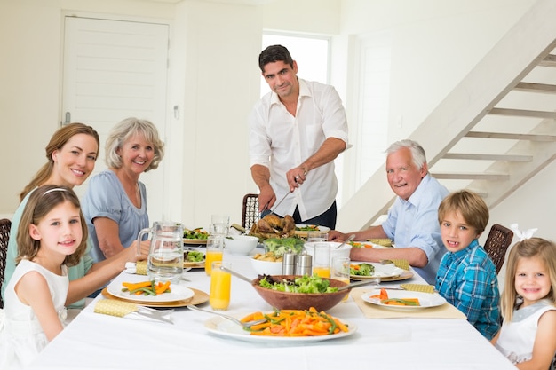 Padre sorridente che serve il pasto alla famiglia