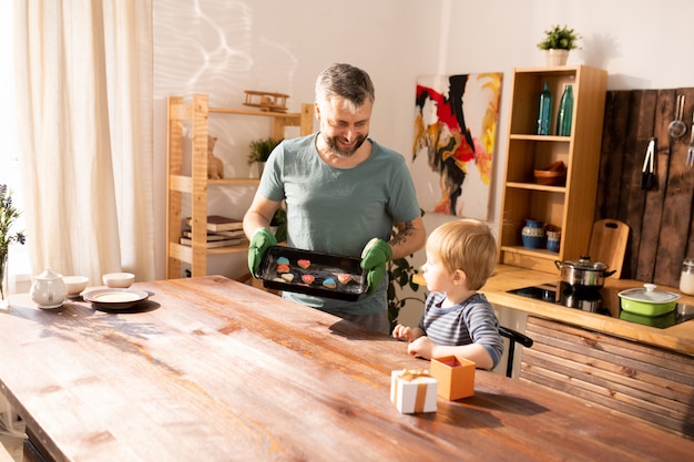 Smiling father showing handmade sugar cookies to son