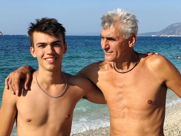 Photo smiling father and son at beach against sky