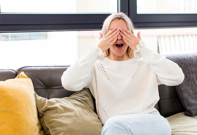 Smiling and feeling happy covering eyes with both hands and waiting for unbelievable surprise