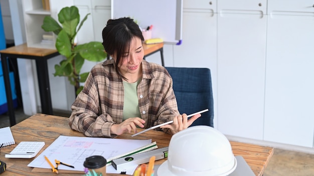 Smiling female architect working on digital tablet in office.