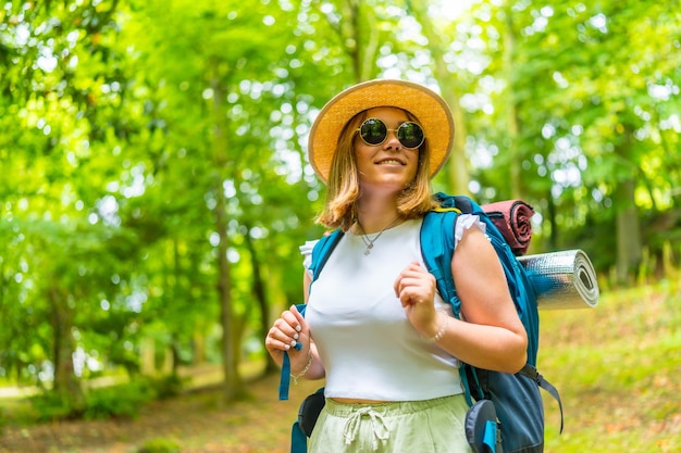 Smiling female backpacker day dreaming in the forest