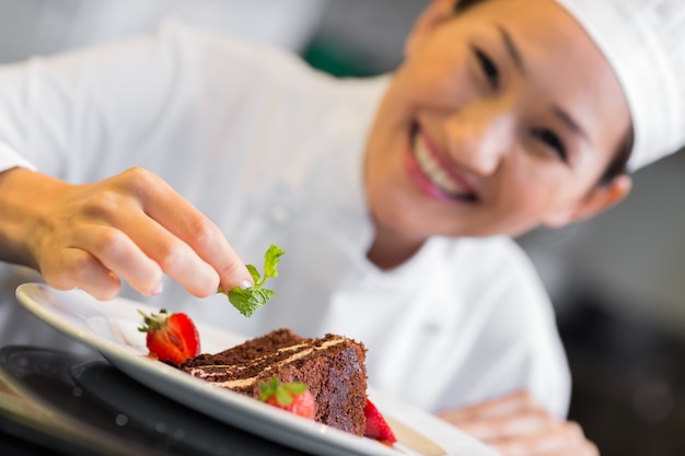 Foto cuoco unico femminile sorridente che guarnisce alimento