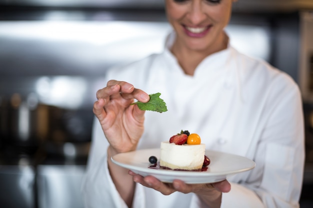 Foto piatto femminile sorridente dell'alimento della tenuta del cuoco unico in cucina