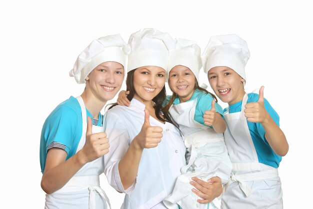 Smiling female chef with assistants showing thumbs up