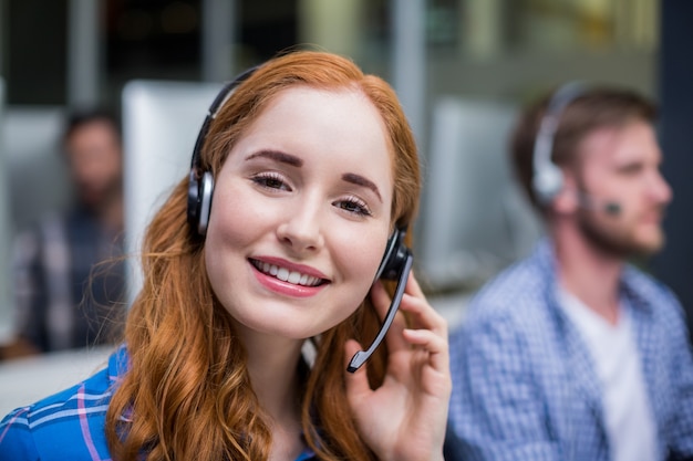 Smiling female customer service executive talking on headset at desk