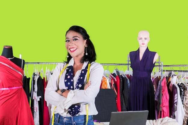 Smiling female designer with folded arms on studio