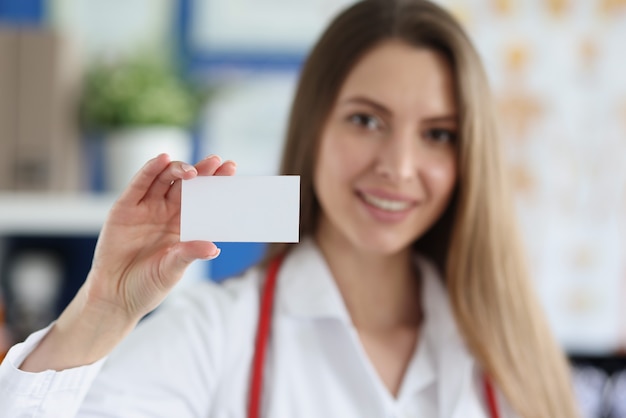 Foto medico femminile sorridente che tiene biglietto da visita bianco white