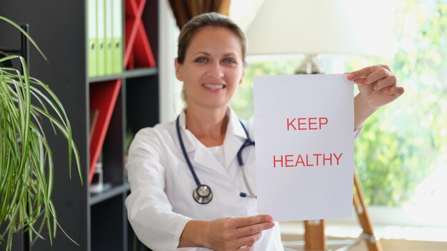 Smiling female doctor is holding inscription keep healthy health insurance and patient refusal