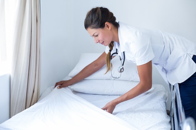 Smiling female doctor preparing the bed