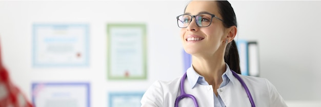 Smiling female doctor shakes hands with patient in hospital medical insurance concept