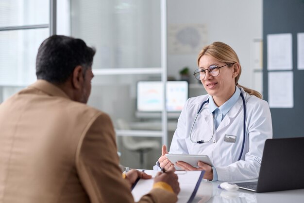 Photo smiling female doctor talking to middle eastern man