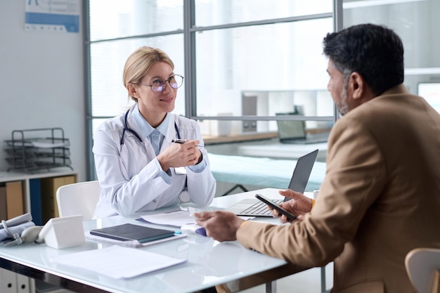 Photo smiling female doctor talking to patient