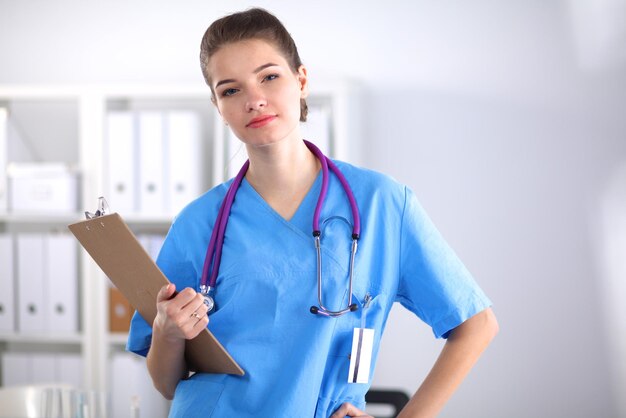 Smiling female doctor with a folder in uniform standing at hospital