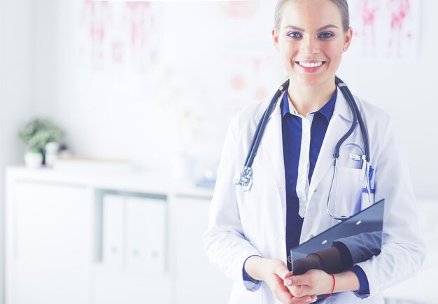 Smiling female doctor with a folder in uniform standing