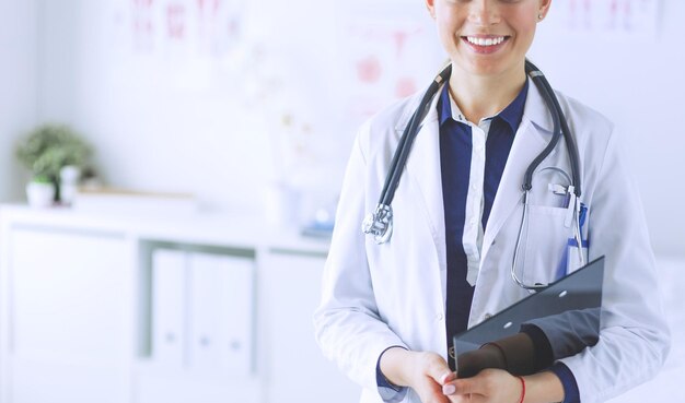 Smiling female doctor with a folder in uniform standing