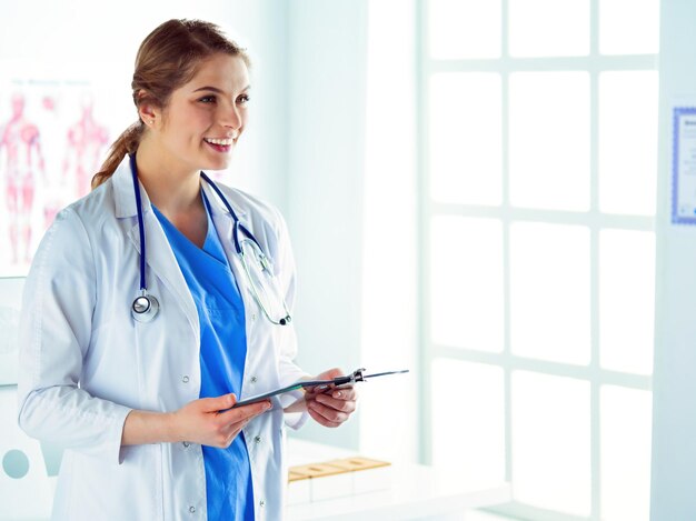 Smiling female doctor with a folder in uniform standing