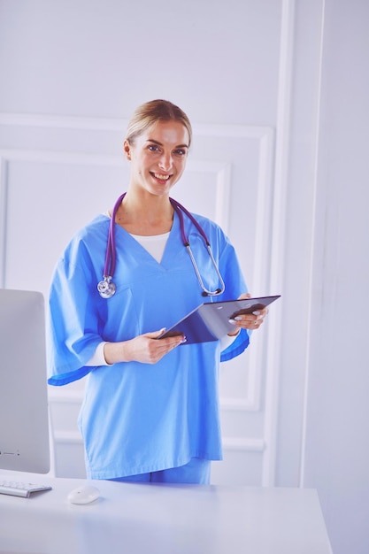 Smiling female doctor with a folder in uniform standing