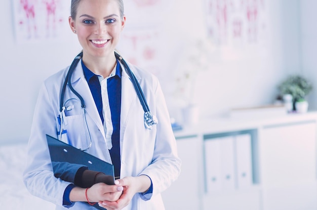 Smiling female doctor with a folder in uniform standing