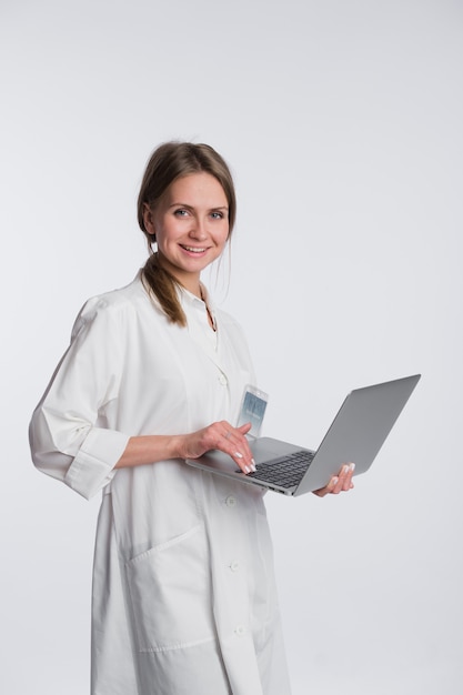 Smiling female doctor working on her laptop against a white