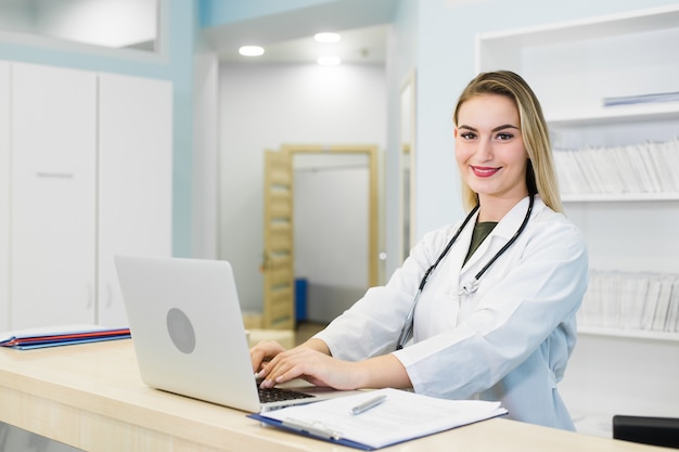 Medico femminile sorridente che lavora alla reception dell'ospedale