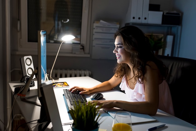 Smiling female entrepreneur working from home late at night