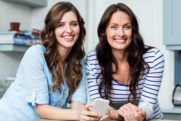 Smiling female friends holding mobile phone