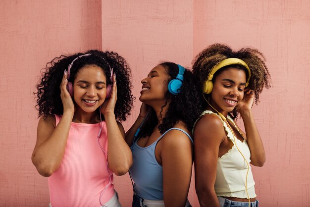 Photo smiling female friends listening music against wall