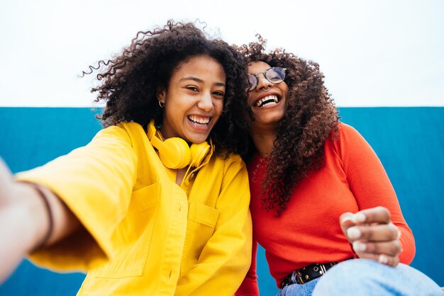 Photo smiling female friends sitting against wall