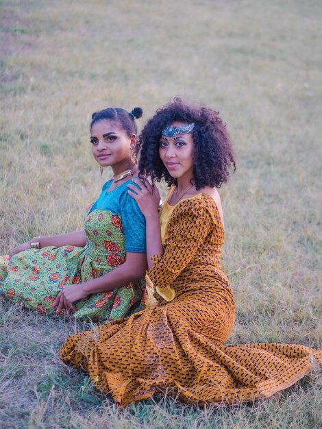 Photo smiling female friends sitting on field