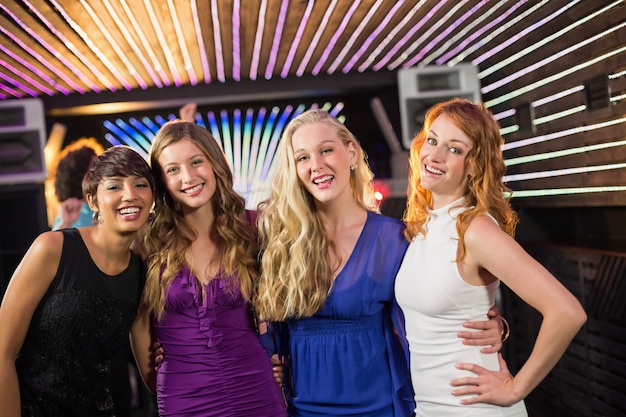 Smiling female friends standing together in bar