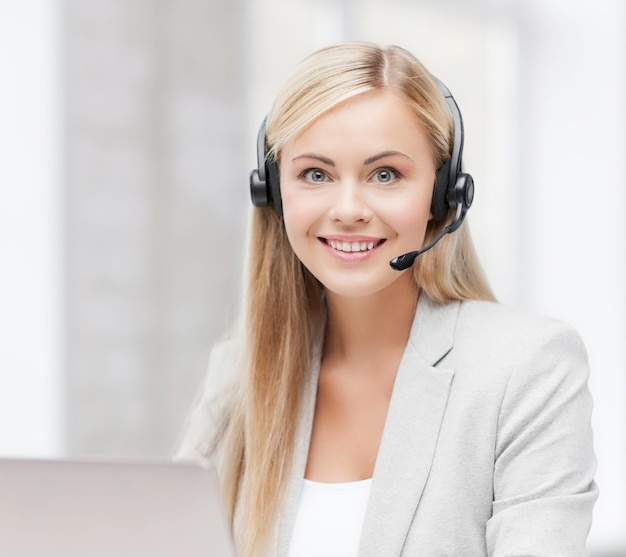 smiling female helpline operator with headphones and laptop