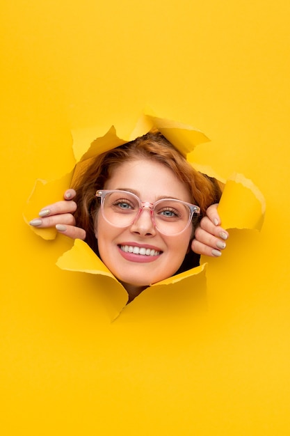 Smiling female looking through torn poster