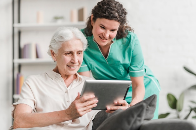 Foto infermiera femminile sorridente e il suo paziente guardando schermo tablet digitale