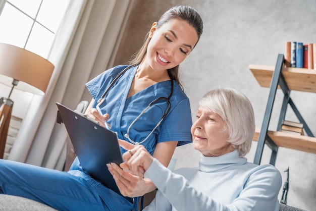 smiling female nurse showing medical tests to senior woman
