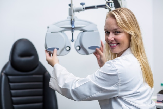 Photo smiling female optometrist adjusting phoropter