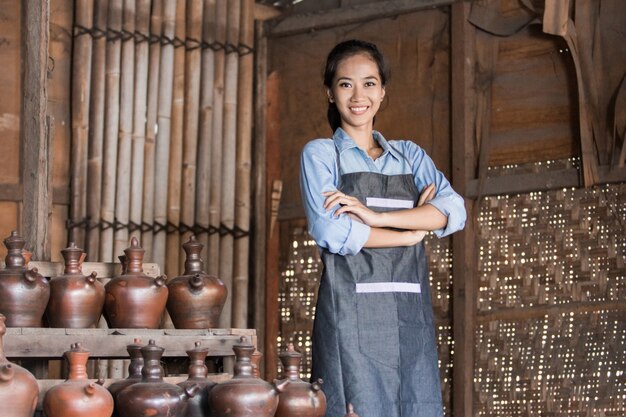 Photo smiling female potter proudly standing in her pottery workshop